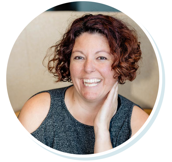 Smiling person with curly hair and gray top.